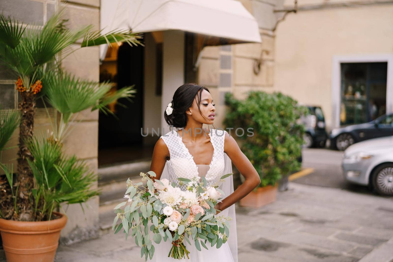 African-American bride in white dress and long veil. With a lush bouquet of the bride in her hands. Wedding in Florence, Italy.