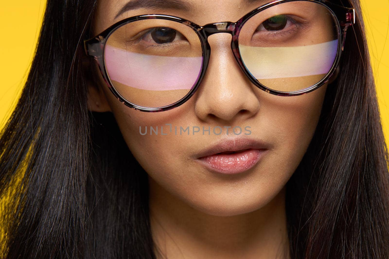 attractive woman asian appearance glasses close-up yellow background glamor. High quality photo