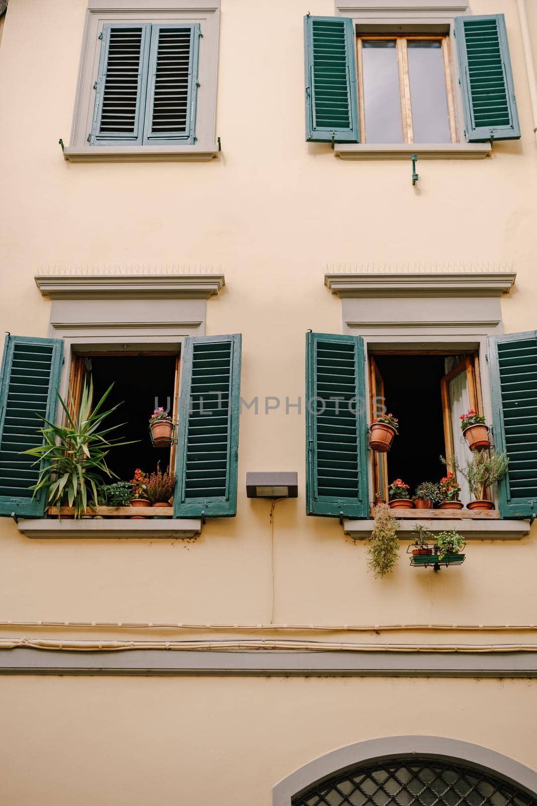 Facade of a residential building in Florence, Italy, with green wooden shutters.