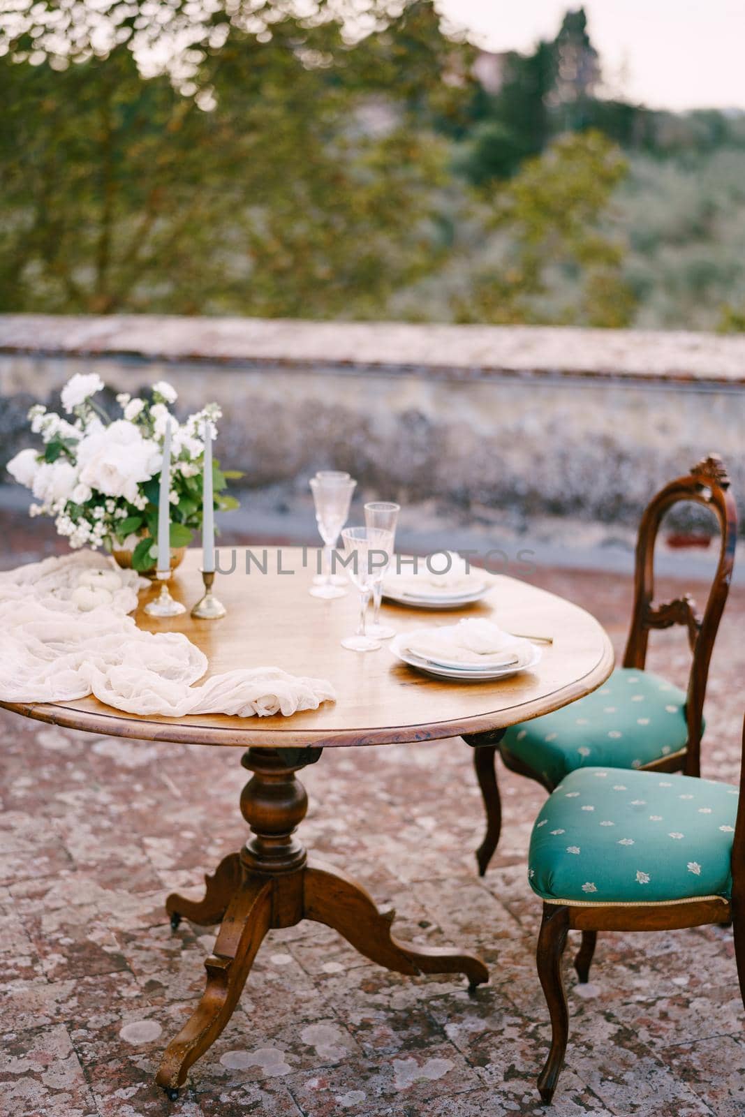 A wooden table and two old chairs, served and decorated for a wedding dinner.