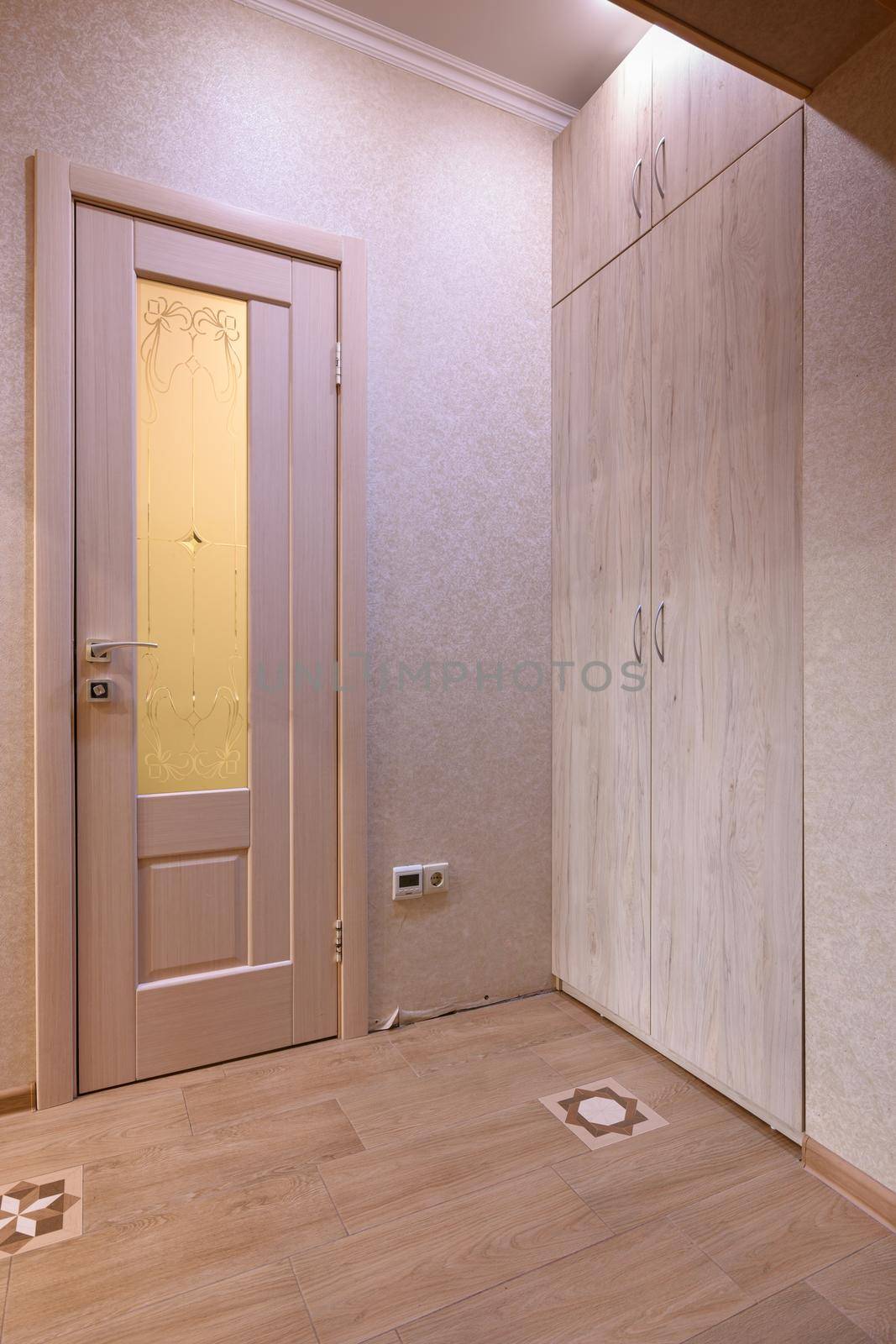 View of the door to the toilet room and a large wardrobe in the interior of the hallway by Madhourse