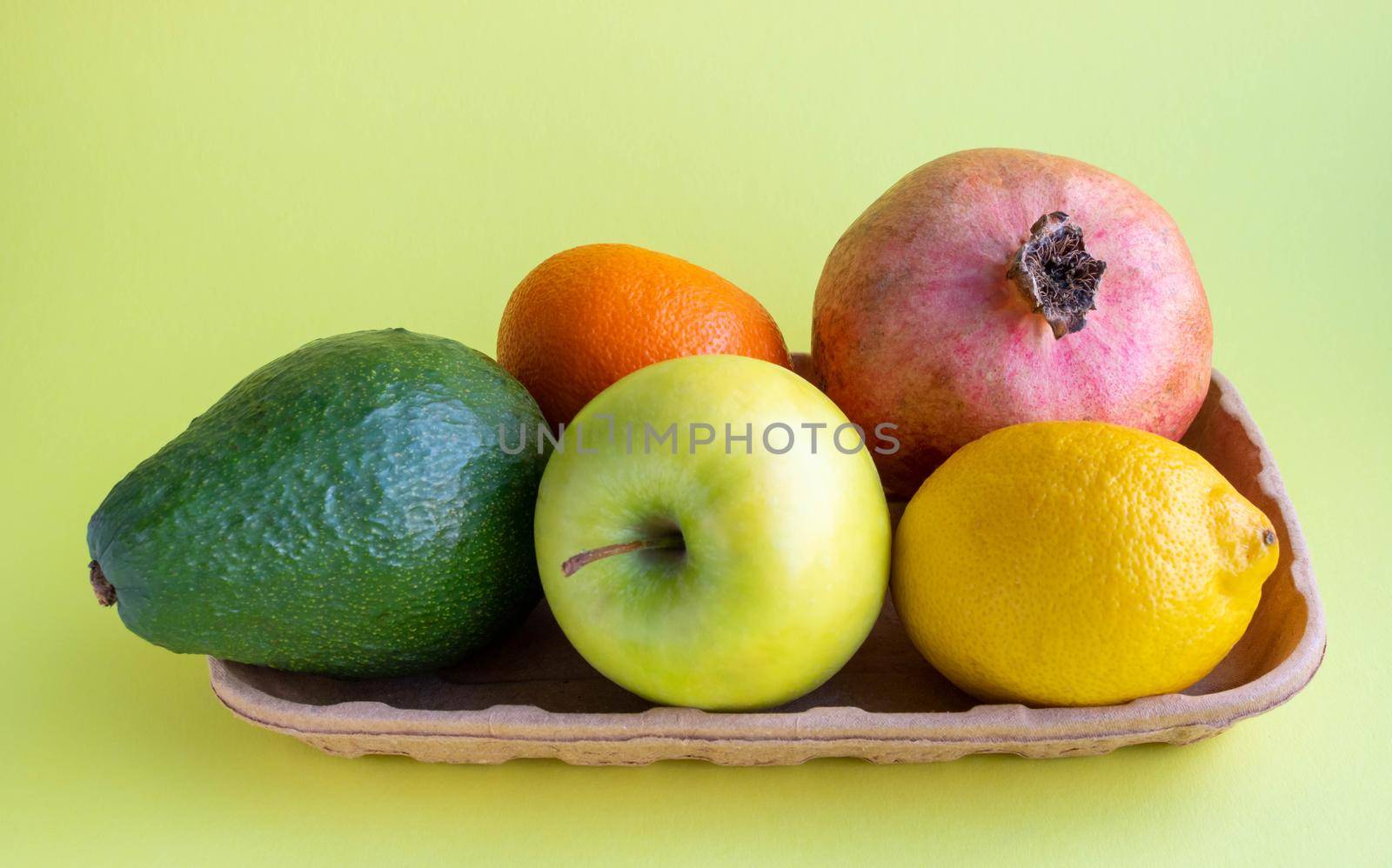 A small collection of fresh fruits in eco-friendly packaging on a yellow background.
