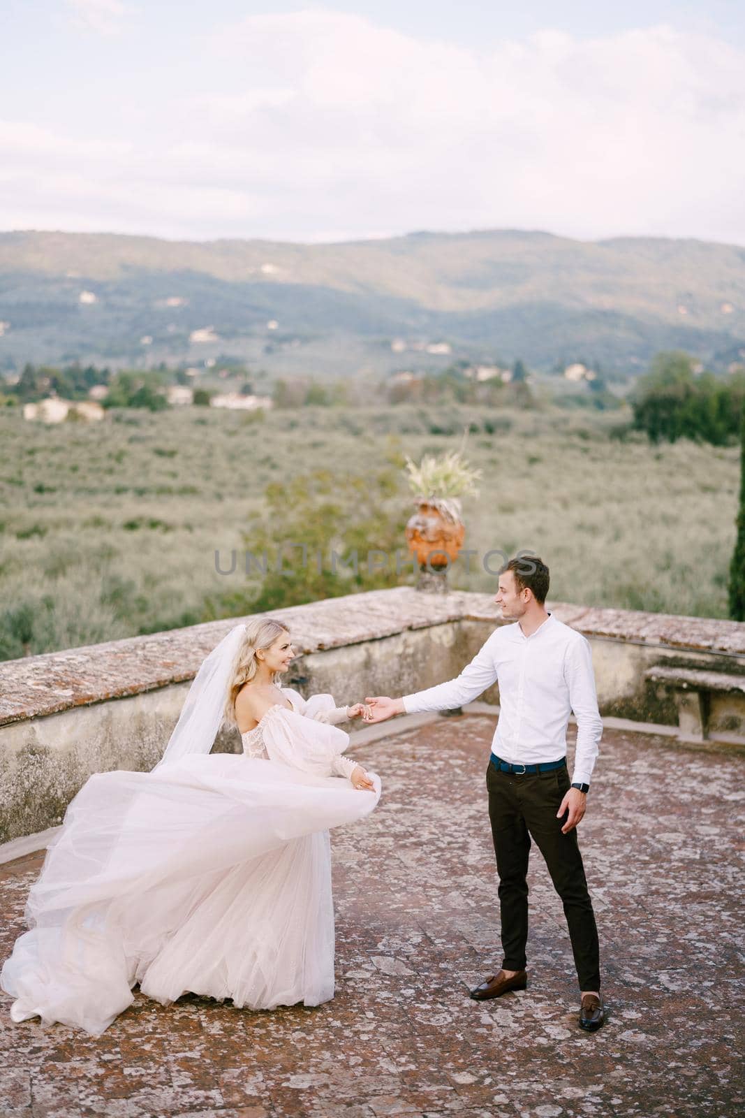 Wedding at an old winery villa in Tuscany, Italy. The bride and groom are dancing on the roof of the villa. by Nadtochiy