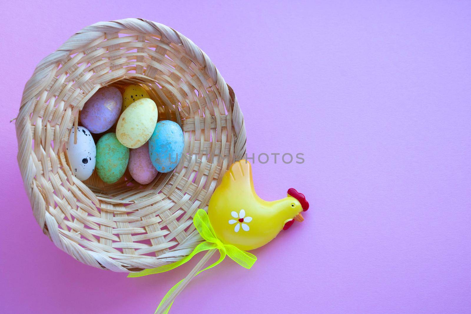 An overturned basket in the shape of a hat with eggs on a pink background. Easter Concept. Space for your text.