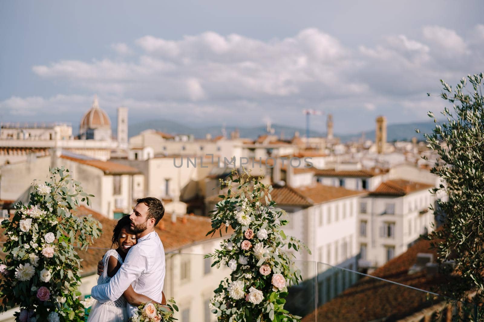 Interracial wedding couple. Destination fine-art wedding in Florence, Italy. A wedding ceremony on the roof of the building, with cityscape views of the city and Cathedral of Santa Maria Del Fiore