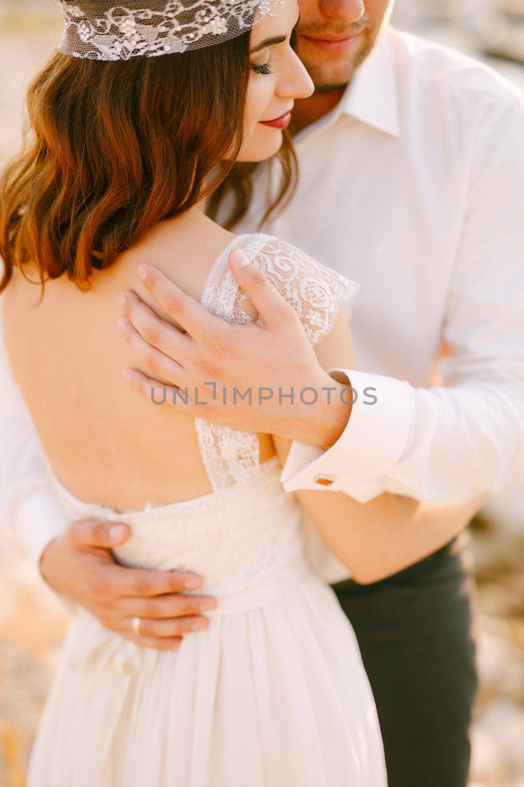 The bride and groom tenderly hug , the groom put his hands on the back of the bride . High quality photo