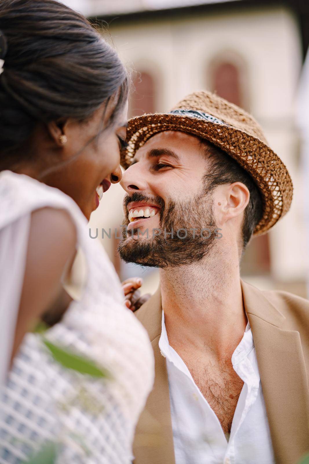 A close-up of portraits of an African-American bride and Caucasian groom in a straw hat. Interracial wedding couple. Wedding in Florence, Italy.