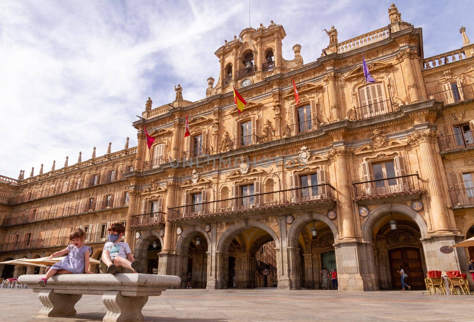 Two children sitting in a bench in front of Salamanca's City Hall at Plaza Mayor