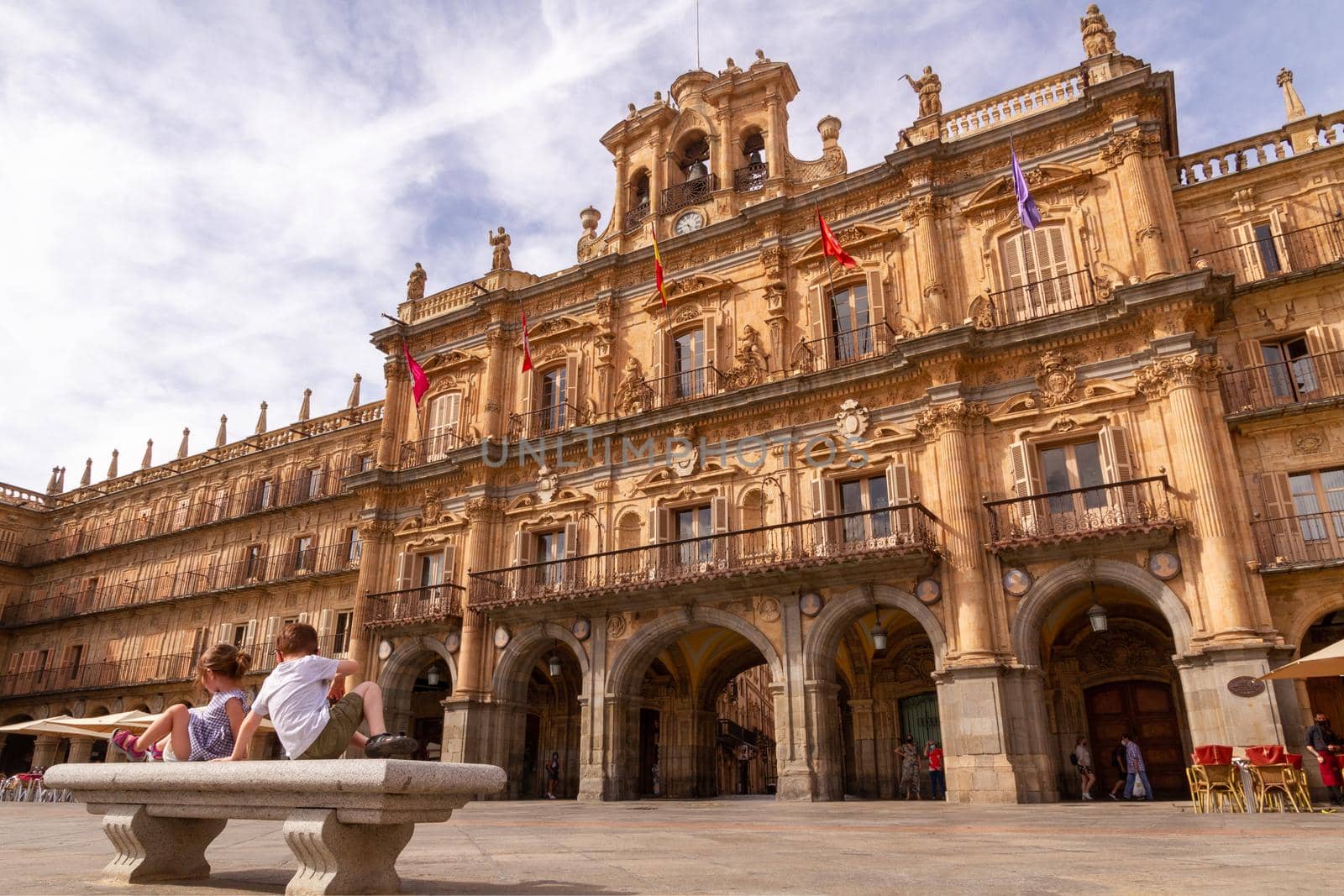 Two children sitting in a bench in front of Salamanca's City Hall at Plaza Mayor