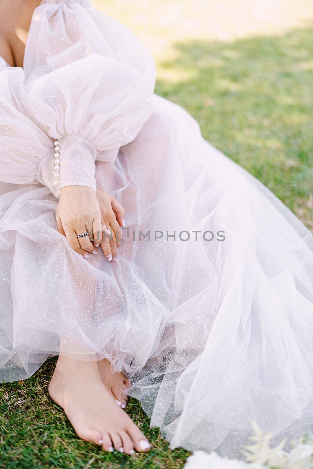 Wedding in Florence, Italy, in an old villa-winery. Barefoot legs of the bride on the grass, next to shoes and bouquet.