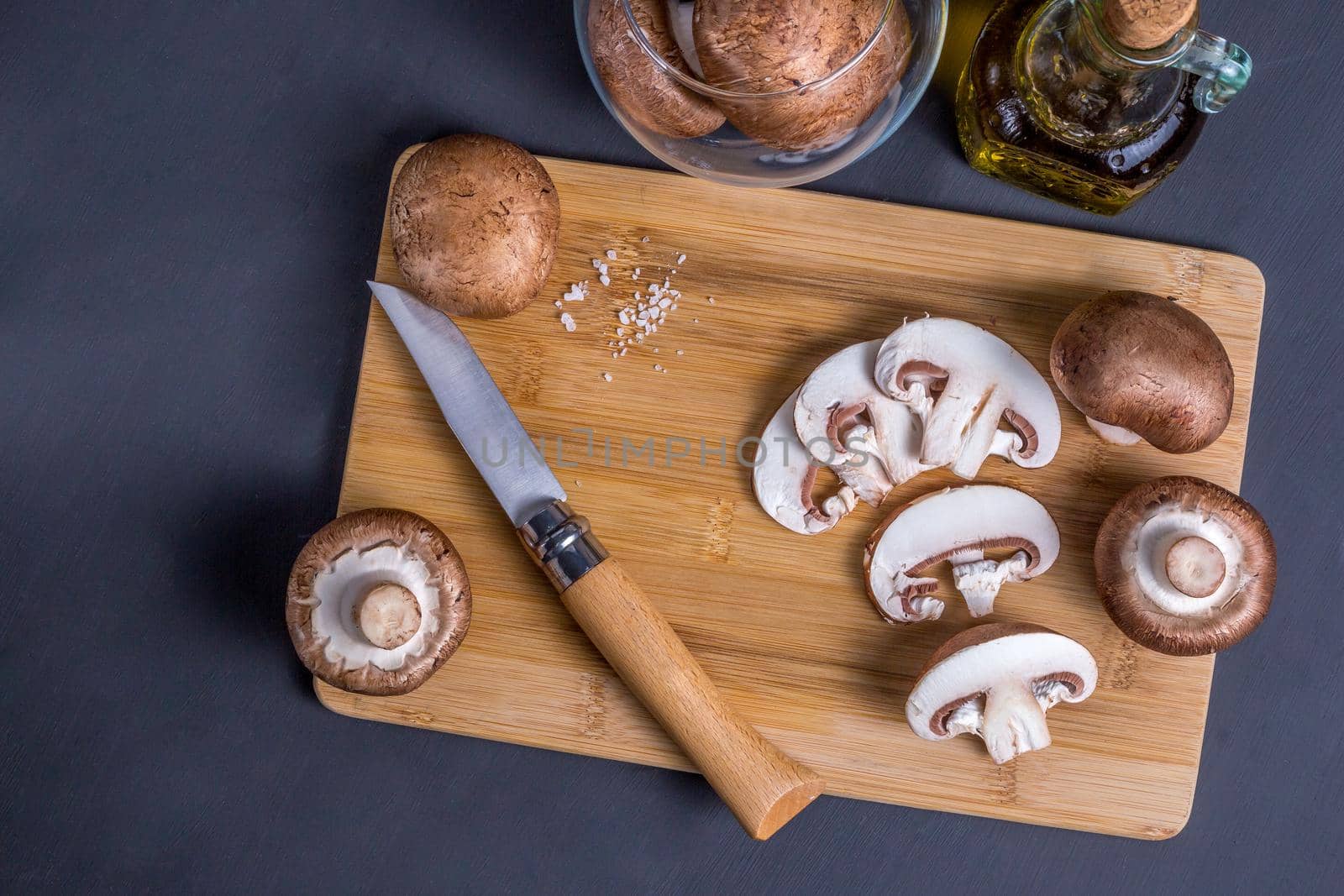 Still life of mushrooms, Royal champignons on a cutting board with knife and a bottle with olive oil, top view