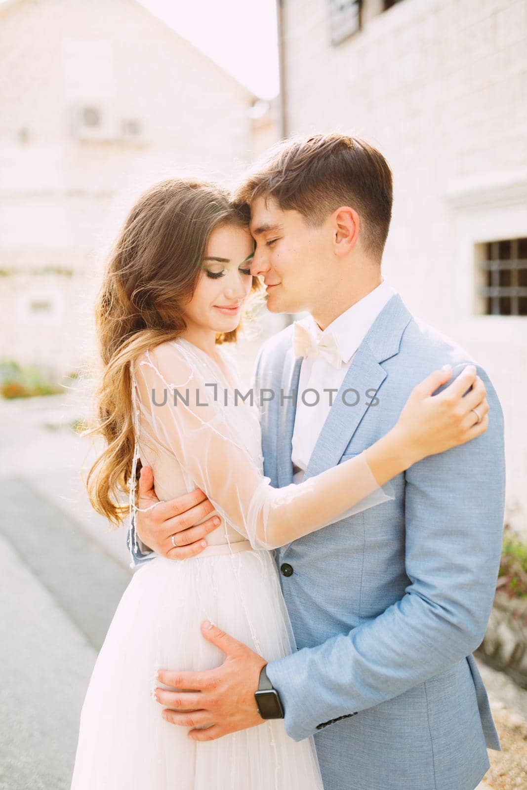 The bride and groom are tenderly embracing on the street of the old town of Perast by Nadtochiy