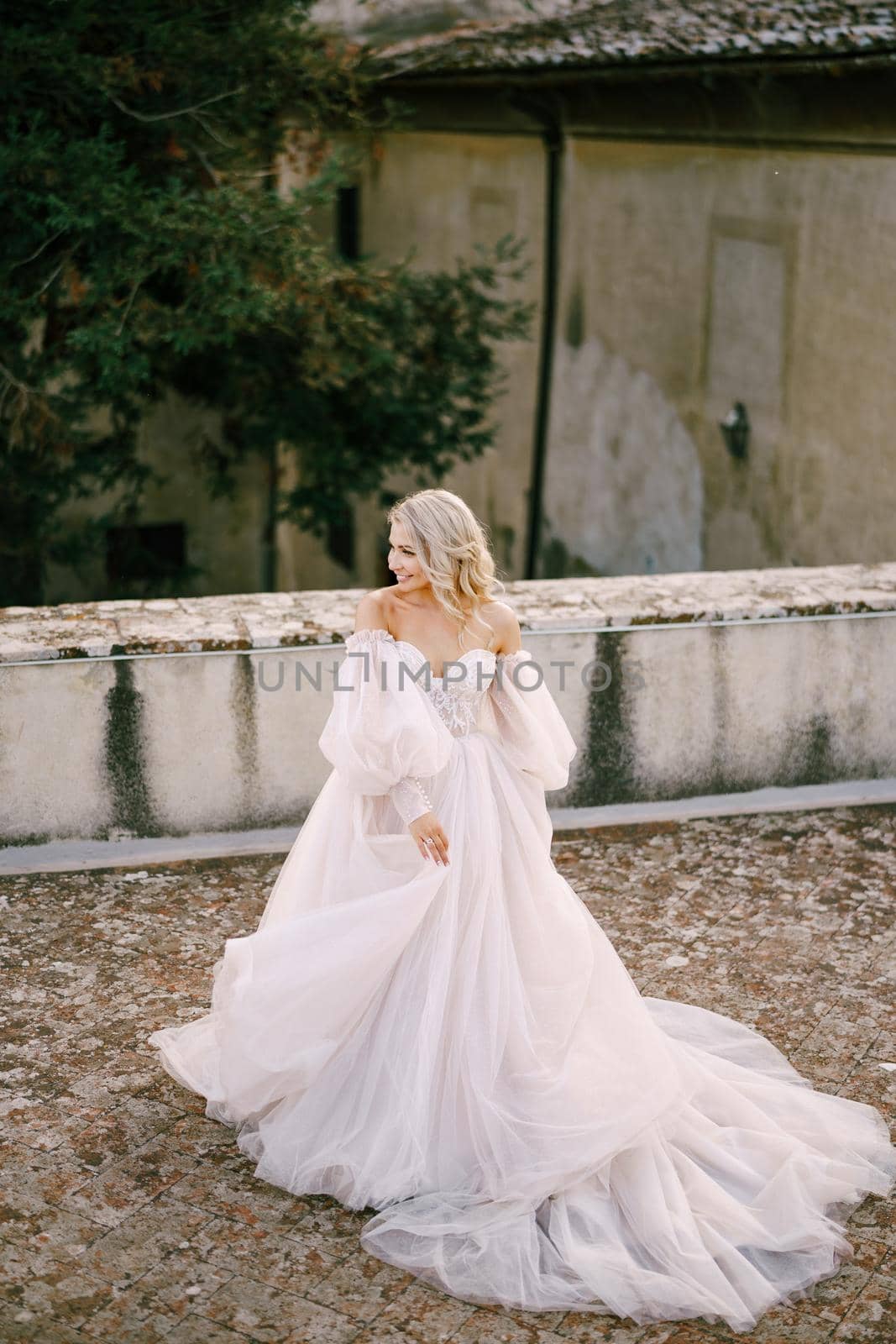 Wedding at an old winery villa in Tuscany, Italy. Bride in a white dress with bare shoulders and sleeves.