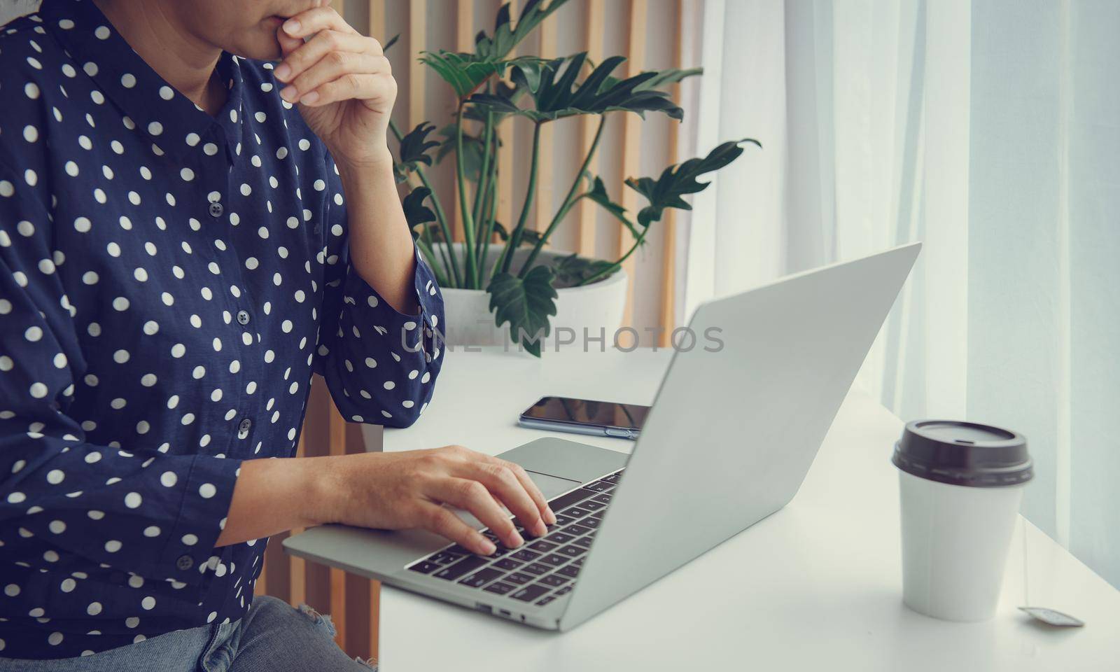 Woman using laptop and thinking about problem solution.Stay at home and work from home concept during Coronavirus pandemic. by thanumporn