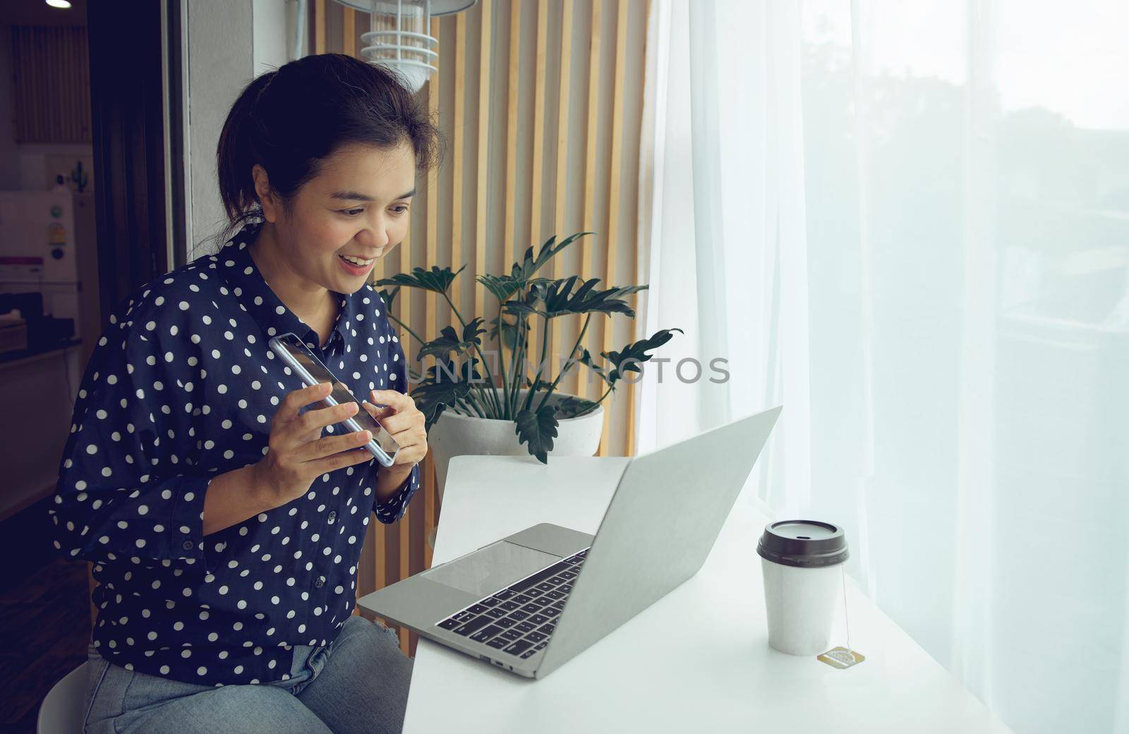 Businesswoman having conference call via laptop and phone.Stay at home and work from home concept during Coronavirus pandemic. by thanumporn