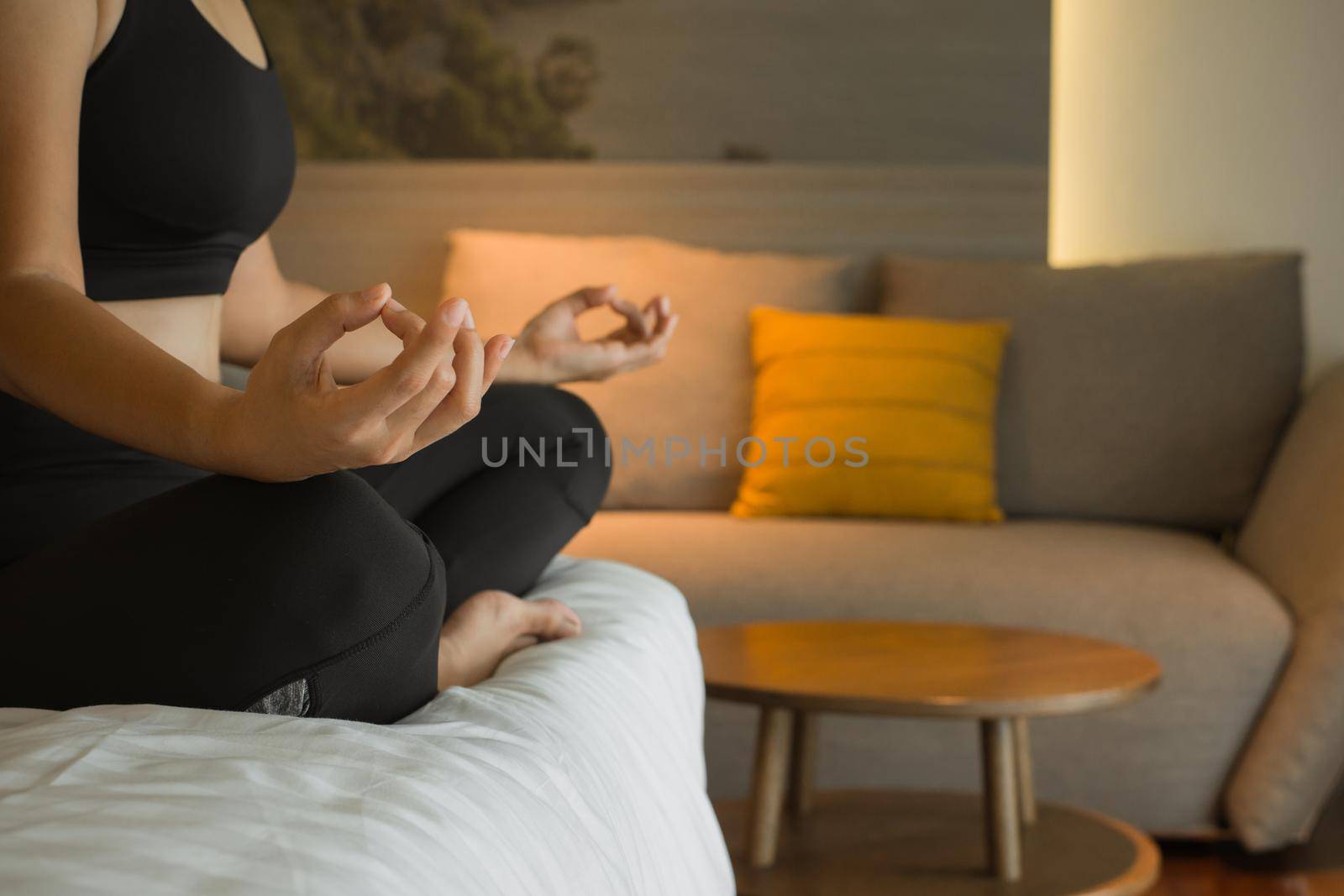 Young woman practice yoga lotus pose to meditation in bedroom after wake up in the morning. Health care and Exercise at home Concept. by thanumporn