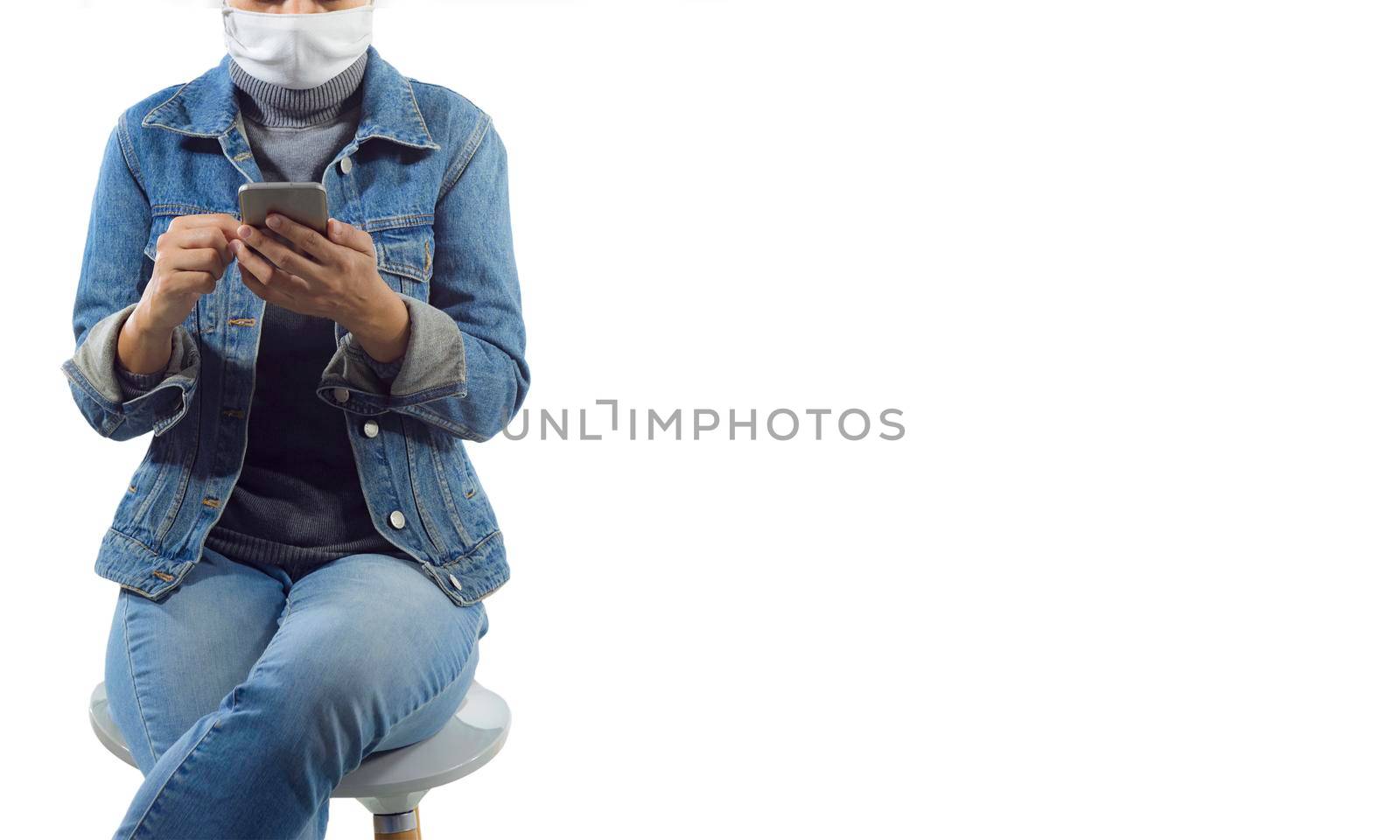 A tourist in medical mask sit on thechair and using mobile phone isolated on white background.Travel and coronavirus concept.