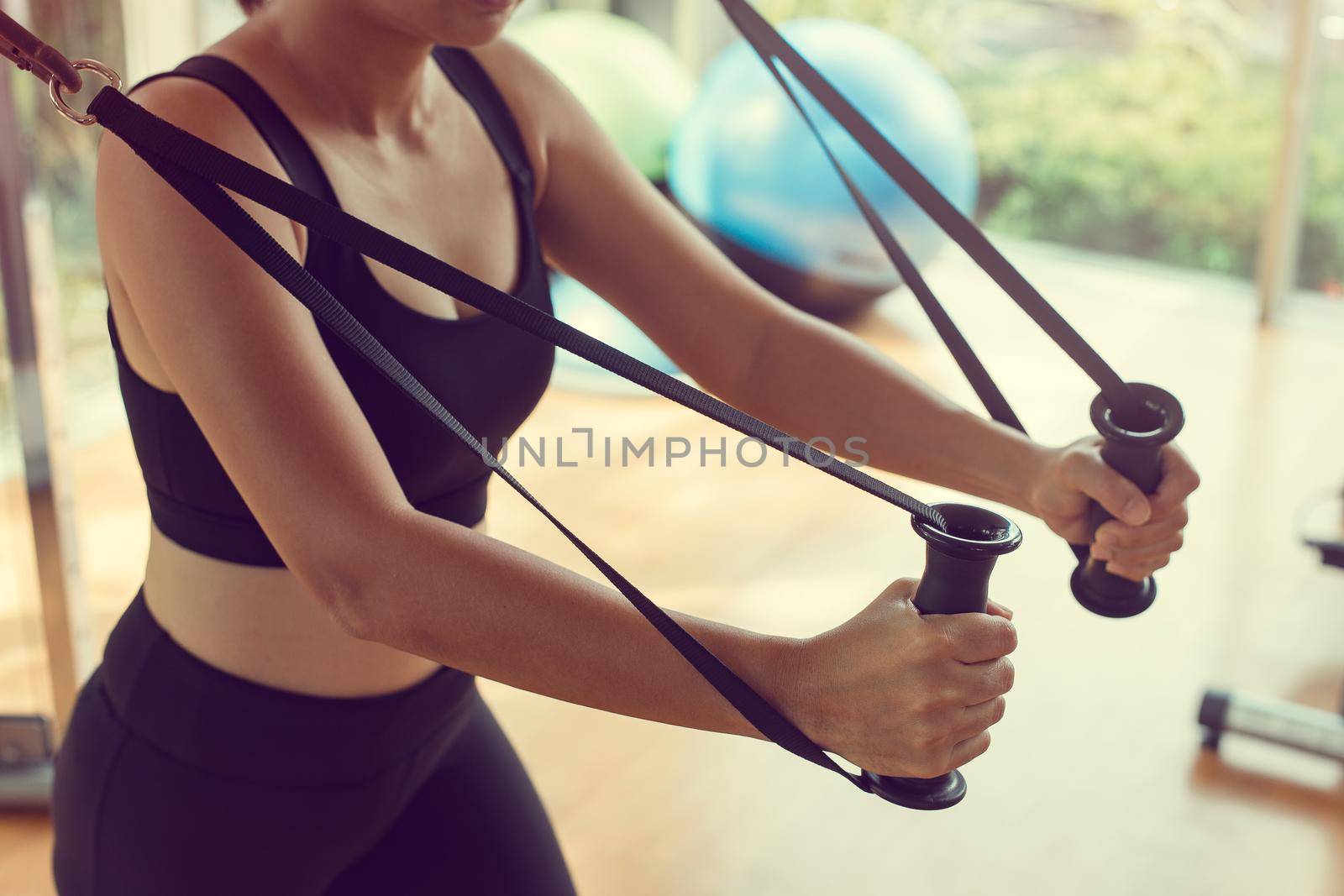 Fit woman workout triceps lifting weights in gym. Athletic woman doing exercise using machine in gym.