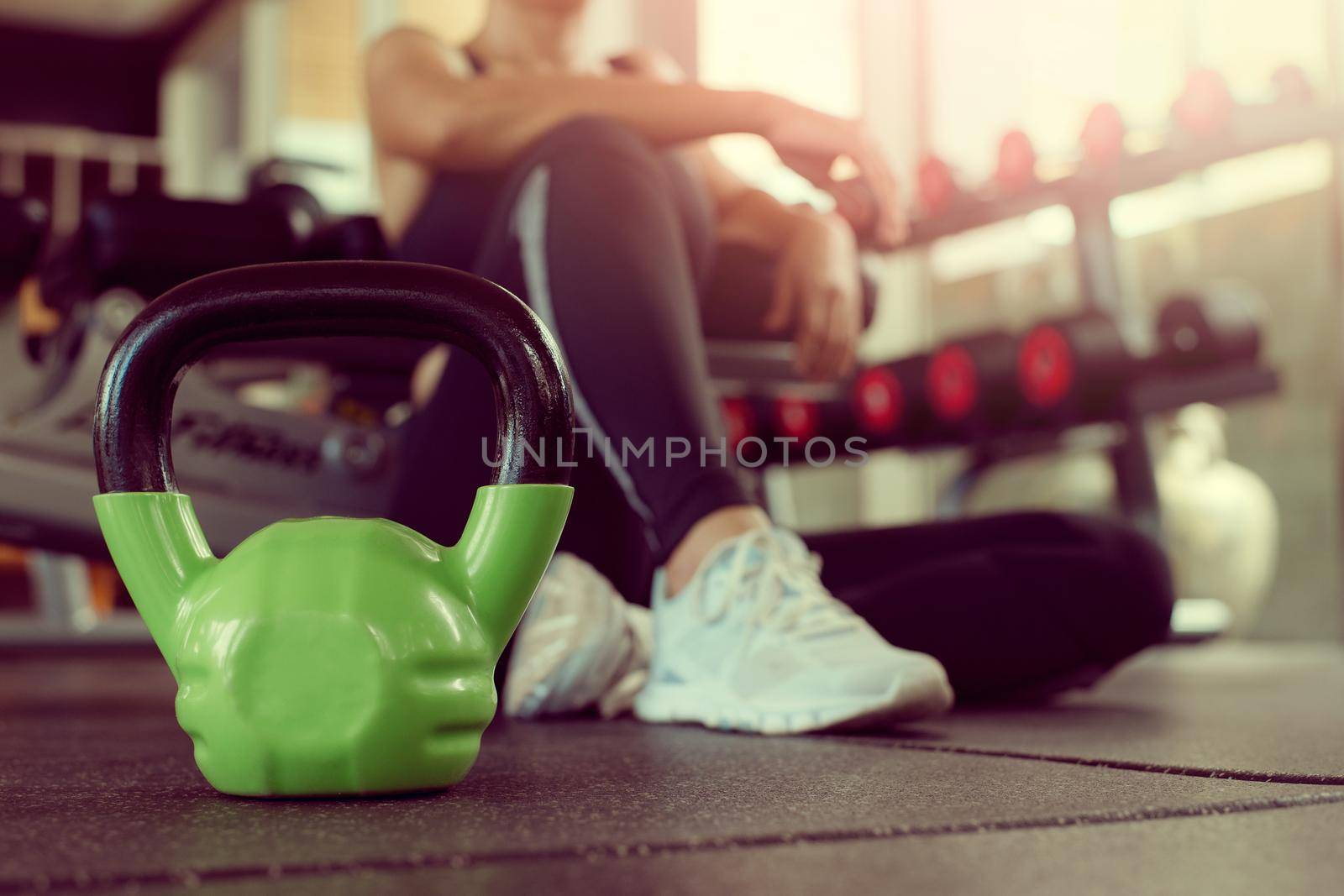 Close up kettlebells with woman exercise workout in gym fitness breaking relax after sport training. Healthy lifestyle bodybuilding and athlete muscles dumbbells.