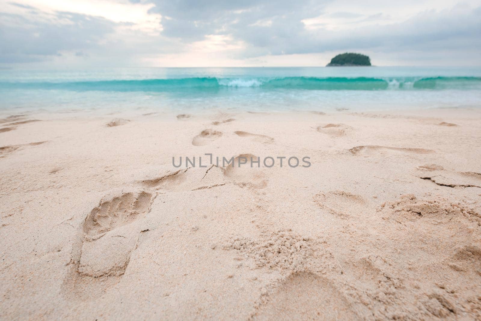 Footprints on beautiful sandy beach and turquoise sea water at sunset time. by thanumporn