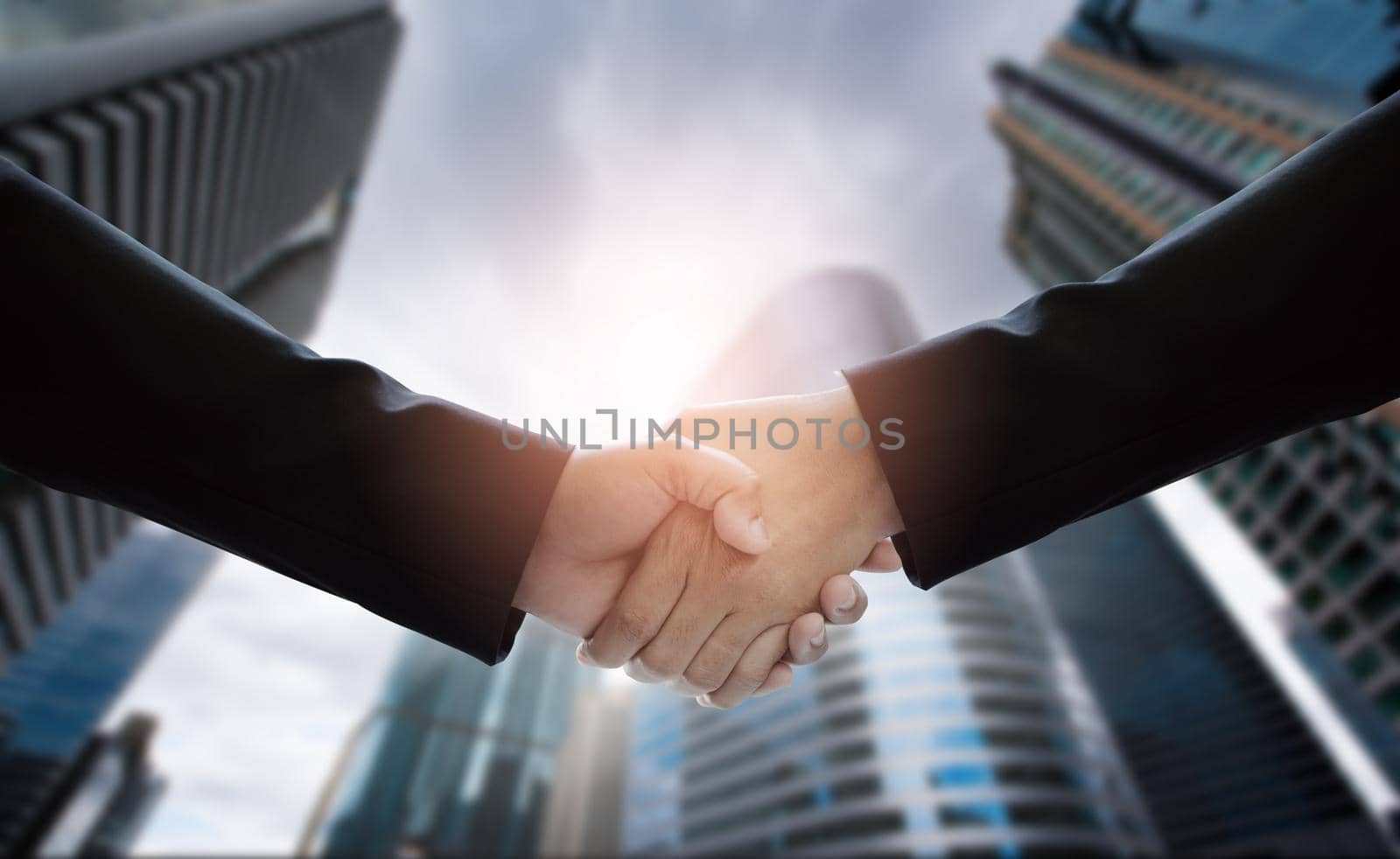 Close-up of business people handshaking on background of modern building. Concepts of financial and economics.