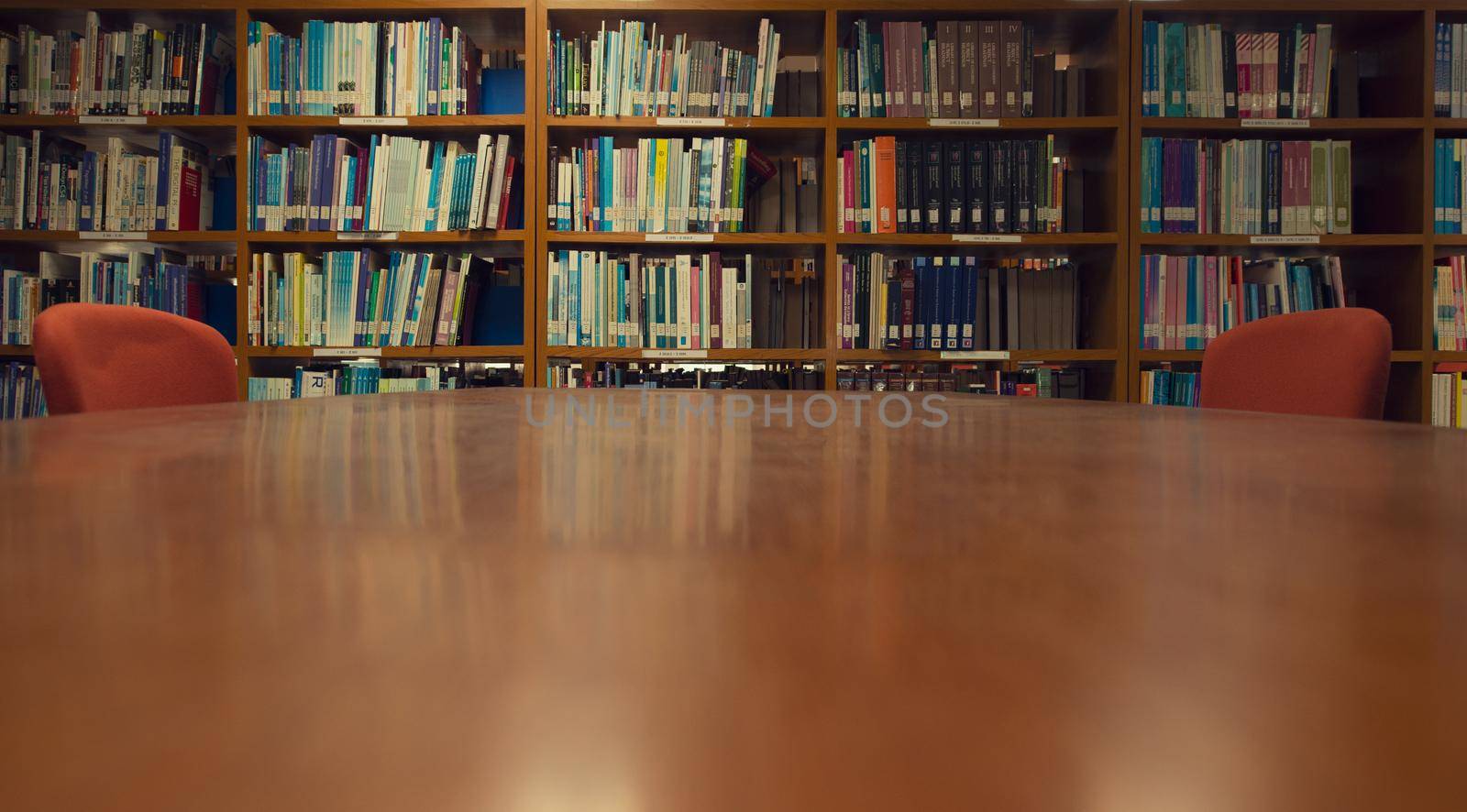 A Wood desk and bookshelf in the library room, Education Concept. by thanumporn