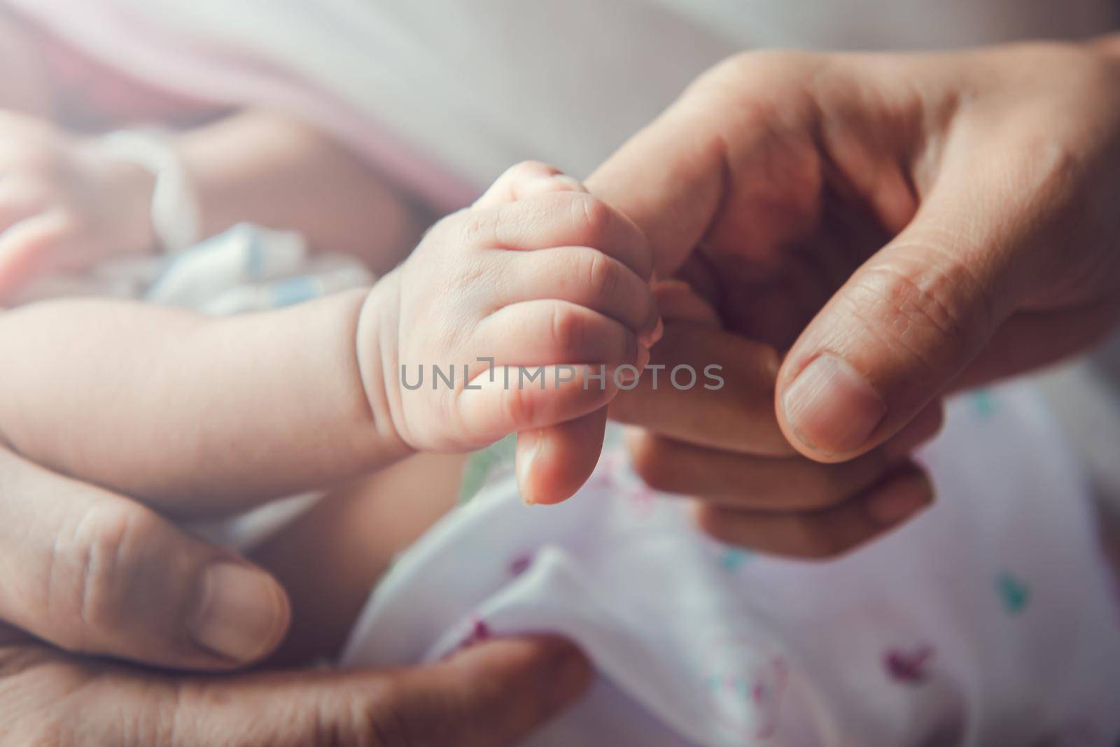 Newborn baby holding mother's hand.