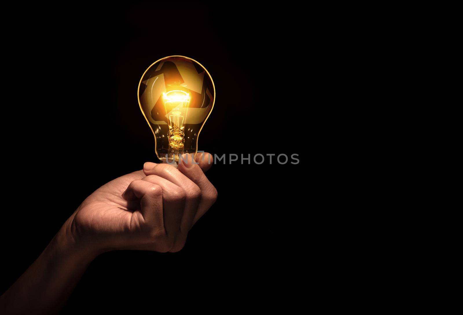 Hand holding bulb with recycle symbol inside isolate on black background.