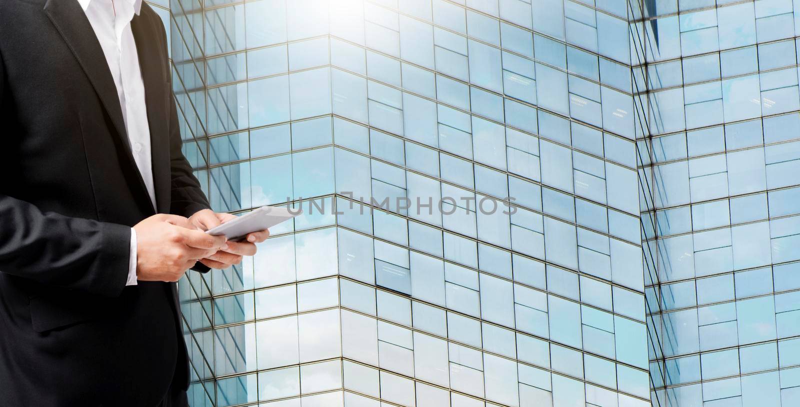 Hands of a businessman using digital tablet with skyscrapers buildings in the background.