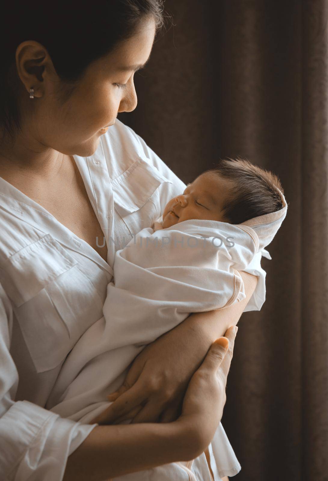 Close-up young woman holding a newborn baby in her arms.