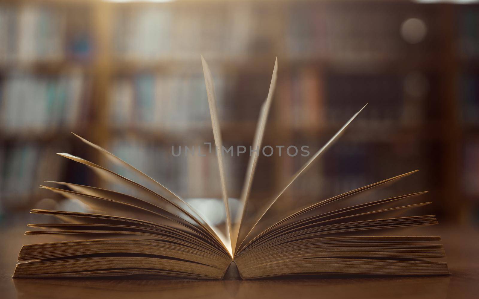Old open book on the table a bookshelf background for academic education learning concept. by thanumporn
