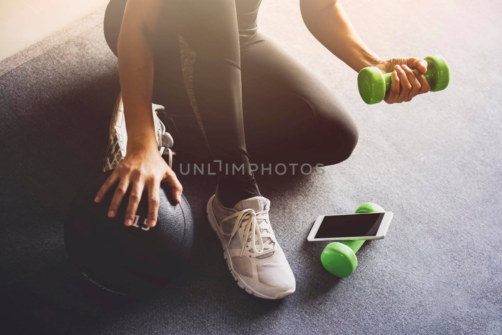 Sporty woman using smartphone during workout at home in the living room.Online personal trainer or on mobile phone.Sport and recreation concept. by thanumporn