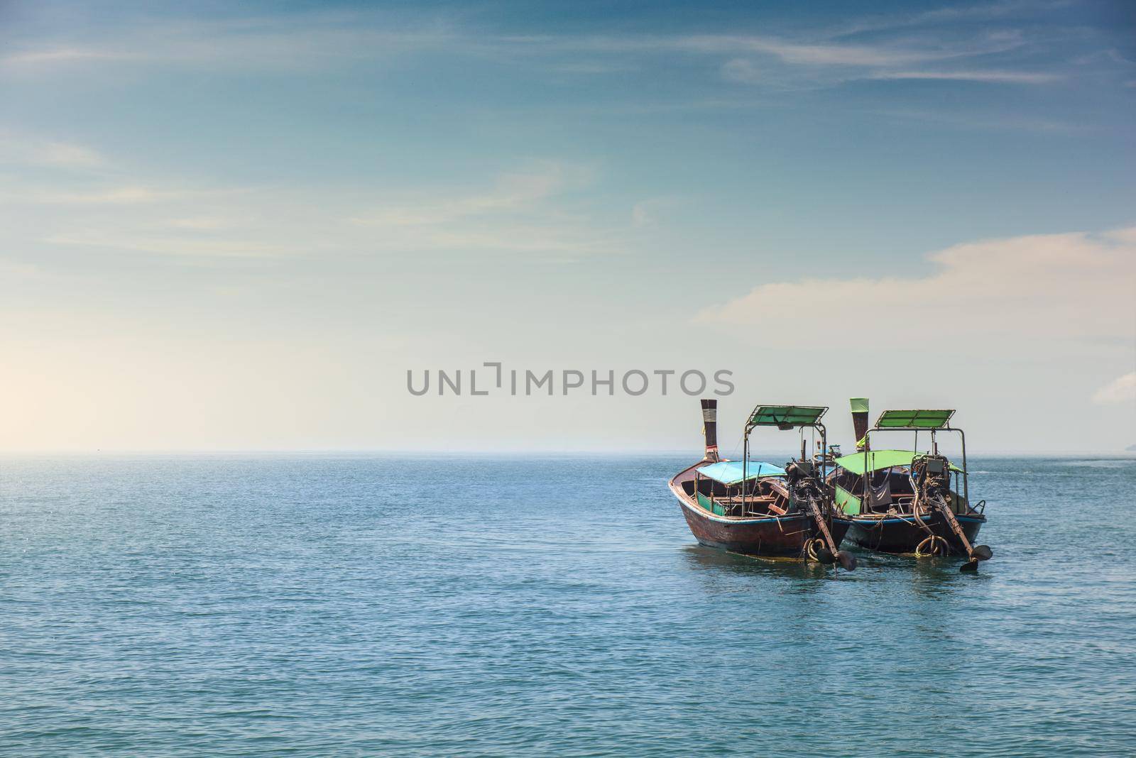 Two long tail boat in sea water is waiting for tourists passengers go back to local islands in the evening. by thanumporn