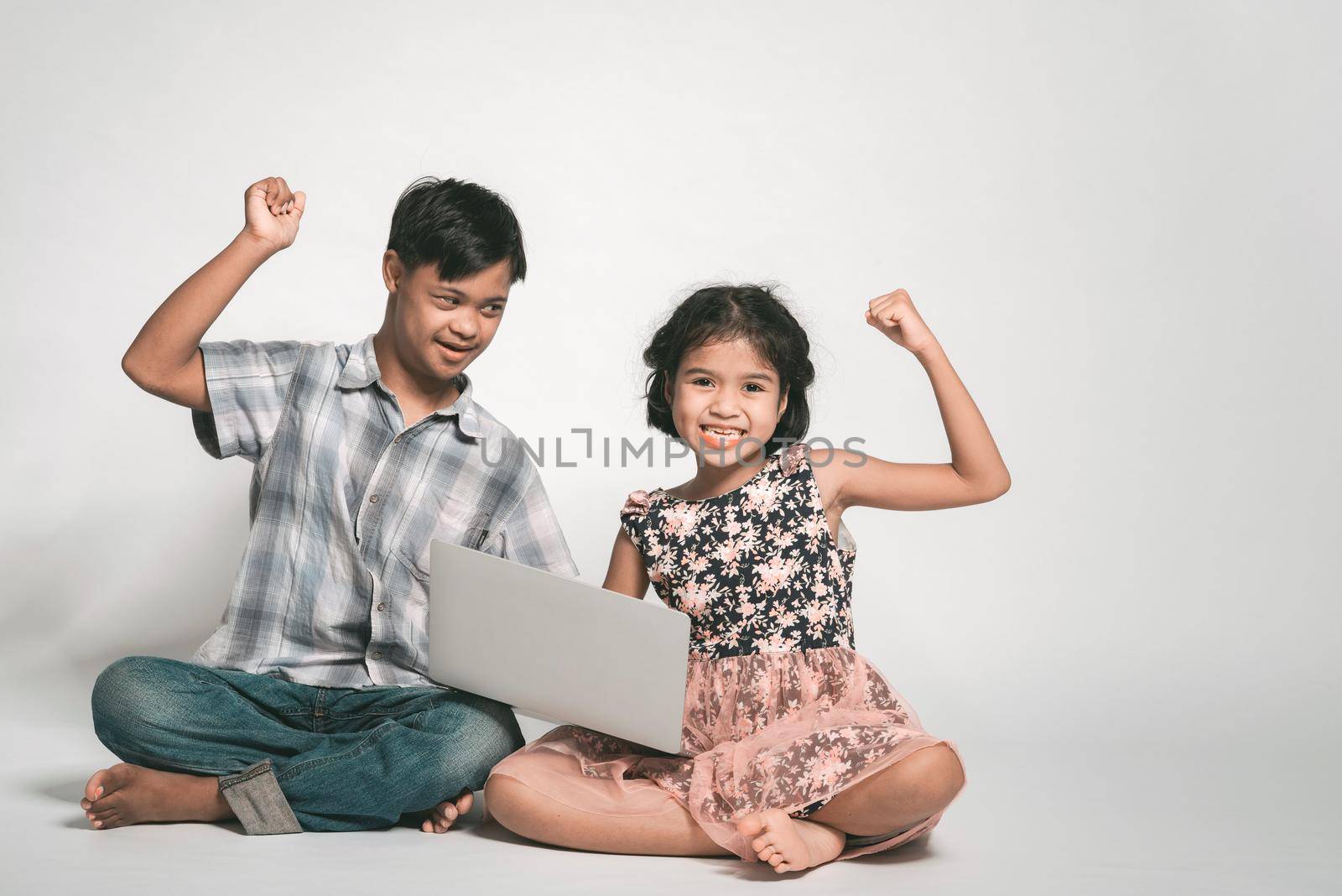 Picture of girl and boy playing laptop. happy feelings, tenderness, care. boy with down syndrome.