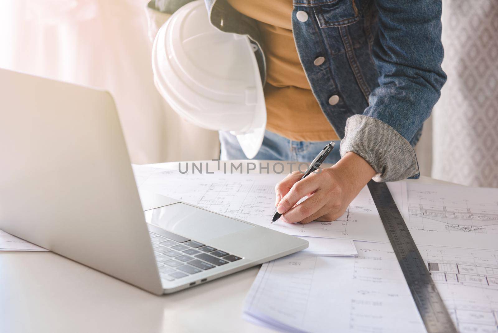 Engineer or architect holding pen with drawings in construction on blueprints in office. Engineering and construction concept.