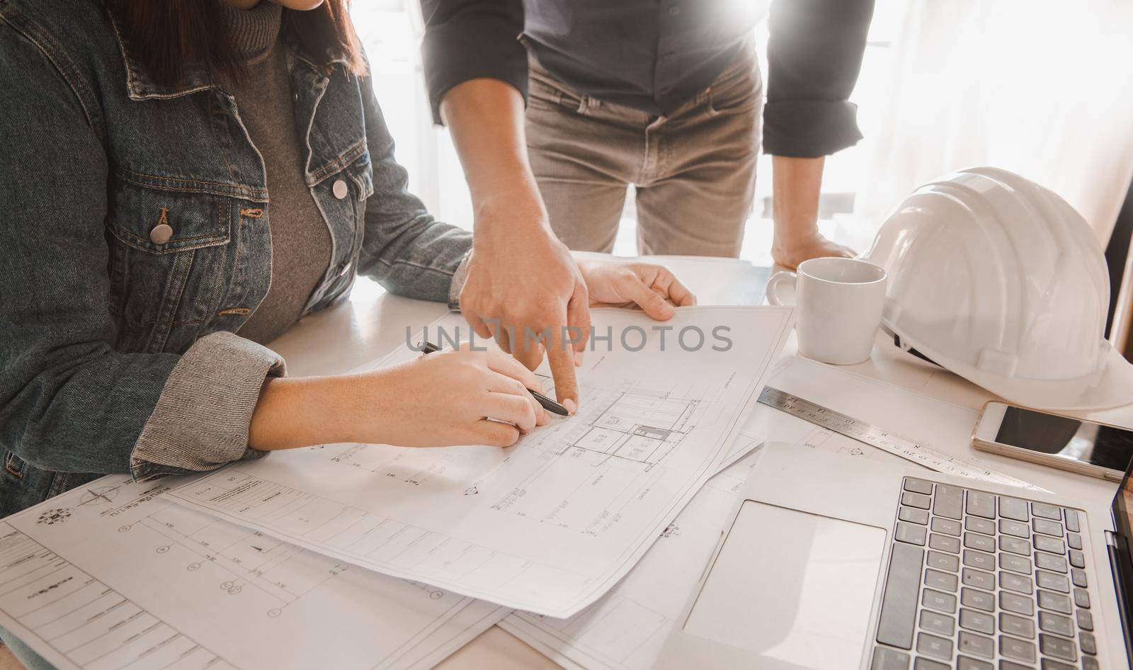 Architects are discussing and planning together at the desk with blueprints.construction & building concept. by thanumporn