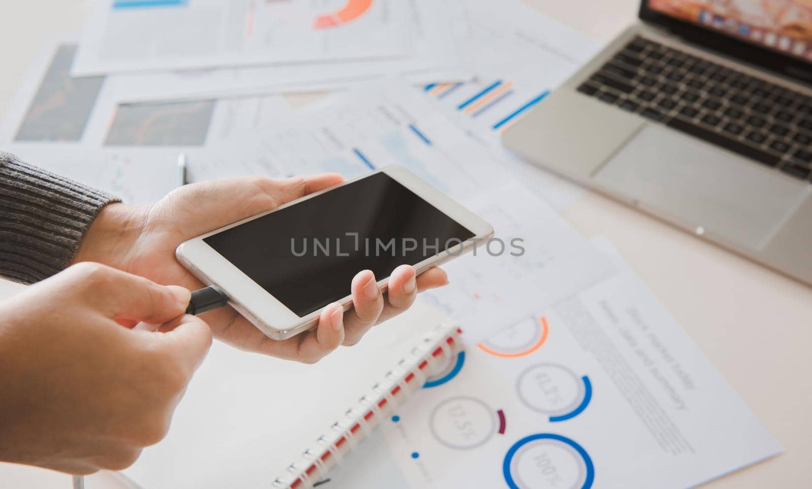 Businesswoman plugging mobile phone to USB charger.