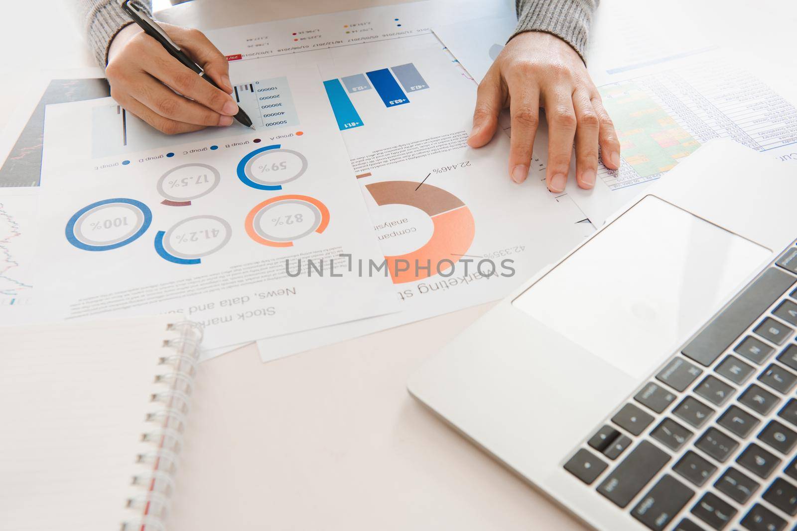 Businesswoman analyze document in his hands.Graphs and diagramm on notebook screen.financial and investment concept. by thanumporn