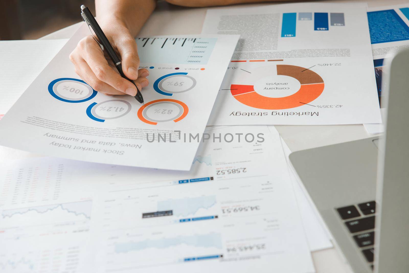 Close up hand Businesswoman holding pen and pointing at financial paperwork and planning investment for business and stocks.