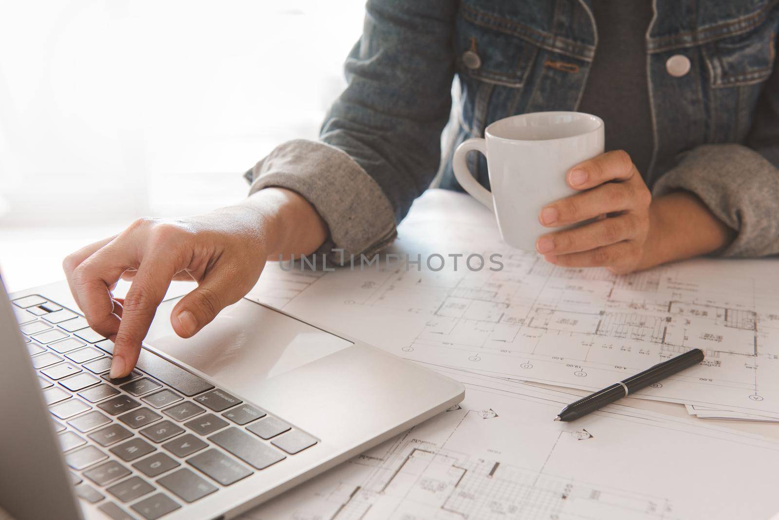 Engineer holding coffee cup while using a computer laptop to  planning project schedule.Engineering and construction concept.