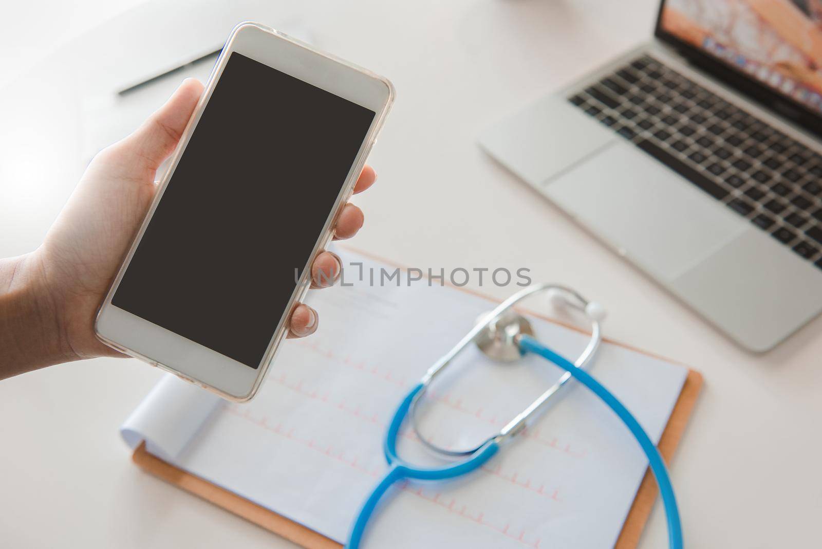 Doctor using mobile phone reading report Treatment on desk.healthcare and technology concept. by thanumporn