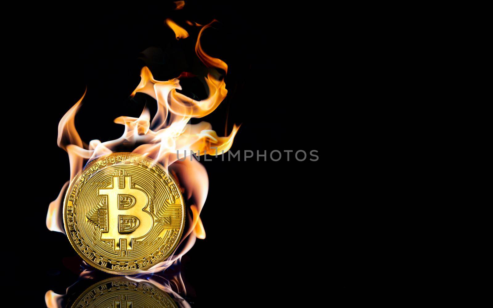 A burnt golden bitcoin on black background with reflection and copy space