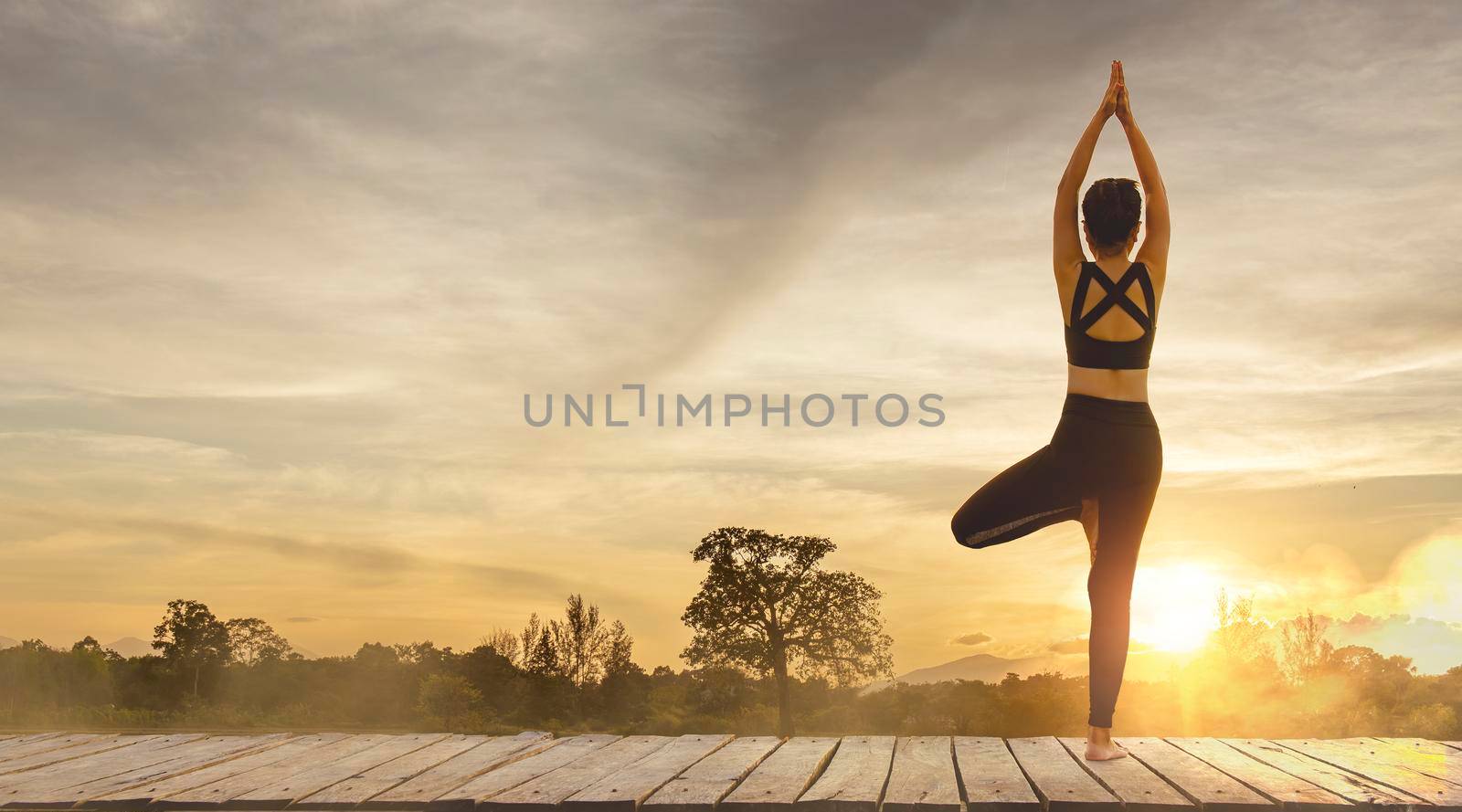 Young woman practicing yoga in the nature.female happiness. Pose balance body vital zen and meditation for workout nature mountain background in morning day. Copy space for banner. by thanumporn