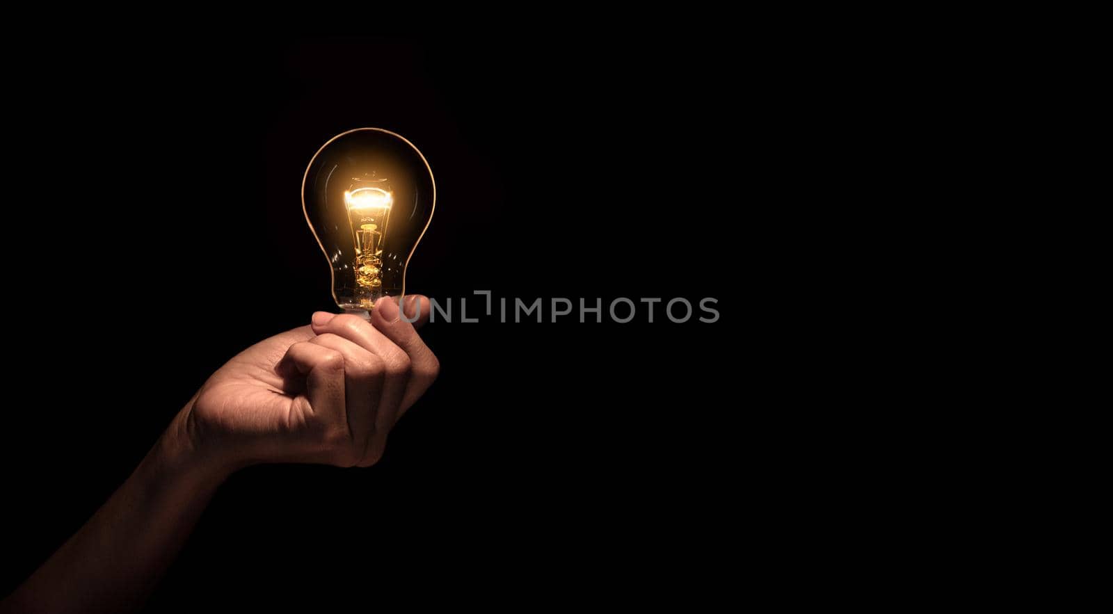 Hand a light bulb isolate on black background.Energy or idea concept