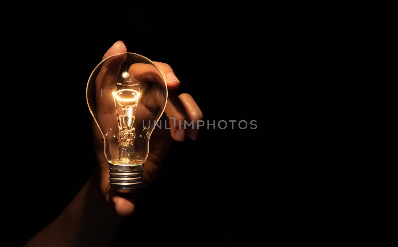 Hand holding light bulb isolated on black background.Energy or idea concept.