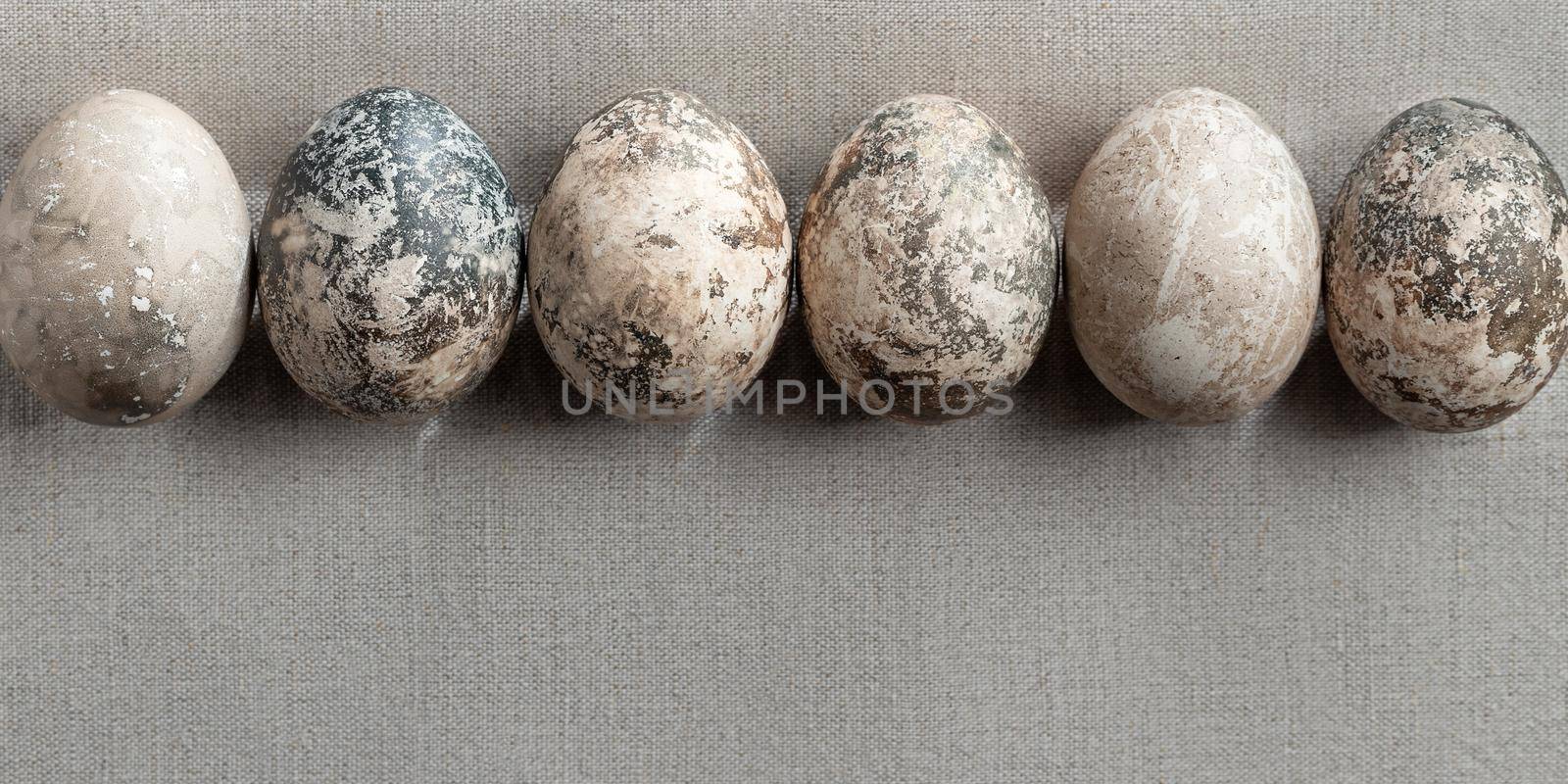 Easter composition - several painted with natural dyes with marble effect on a linen tablecloth in a row.