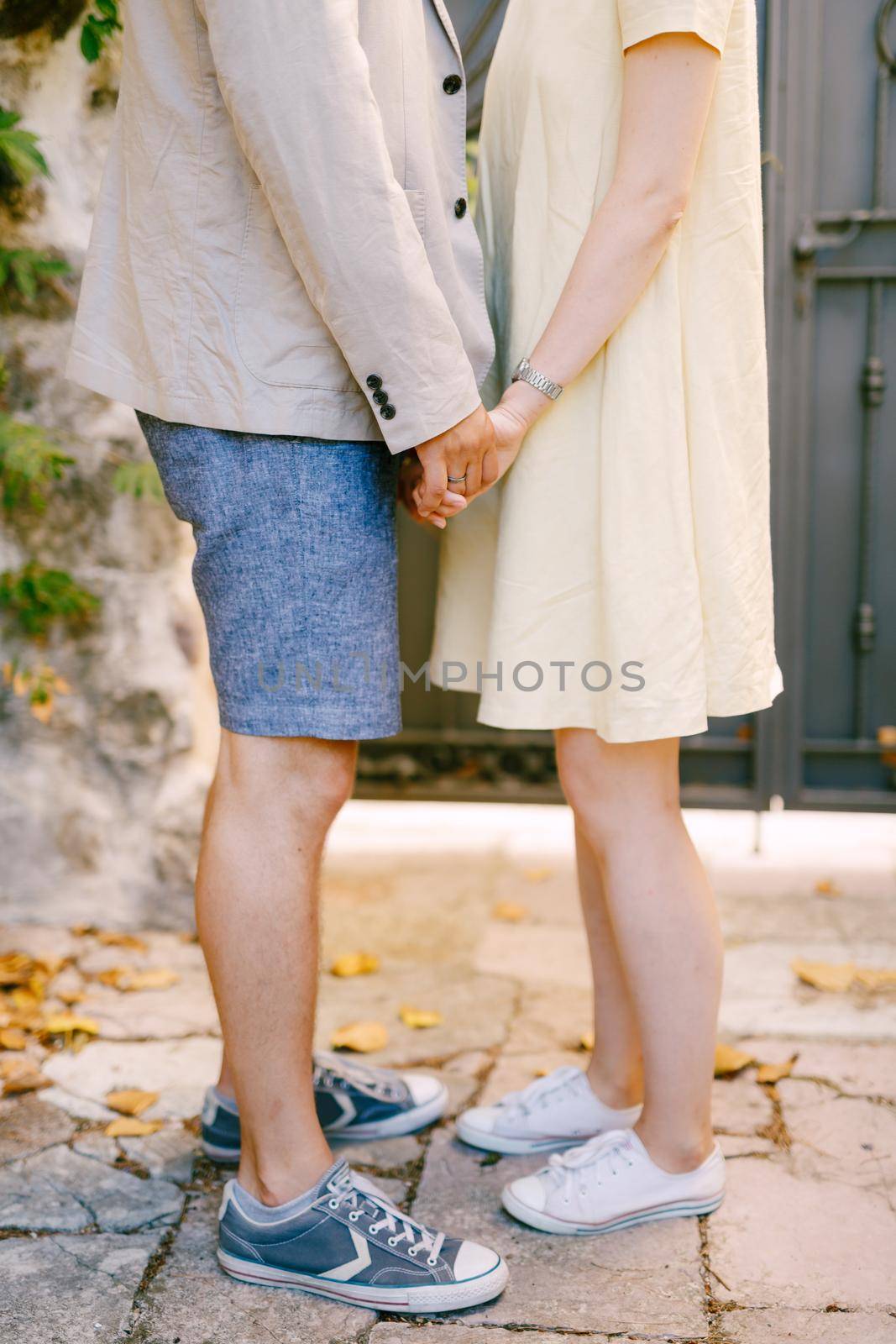 Man and woman are standing on the street holding hands, close-up by Nadtochiy