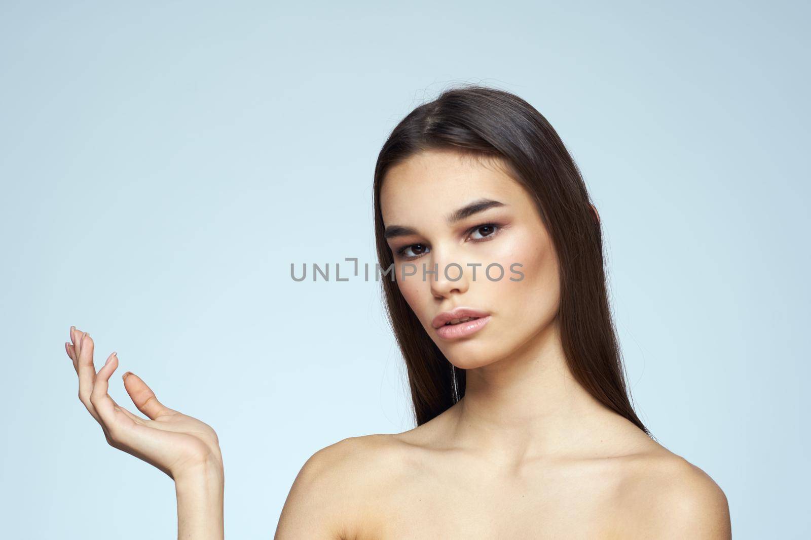 Woman with naked shoulders long hair clean skin cropped view blue background. High quality photo