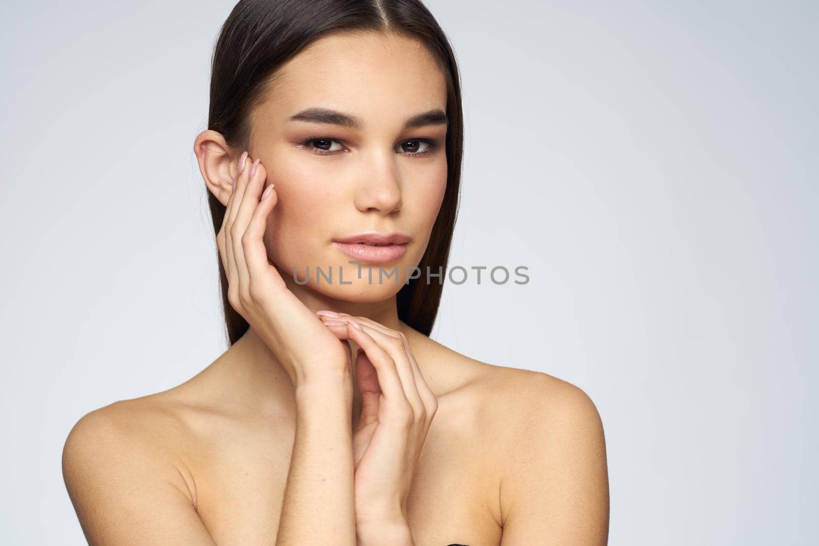 Woman with long hair bared shoulders clean skin body care light background. High quality photo