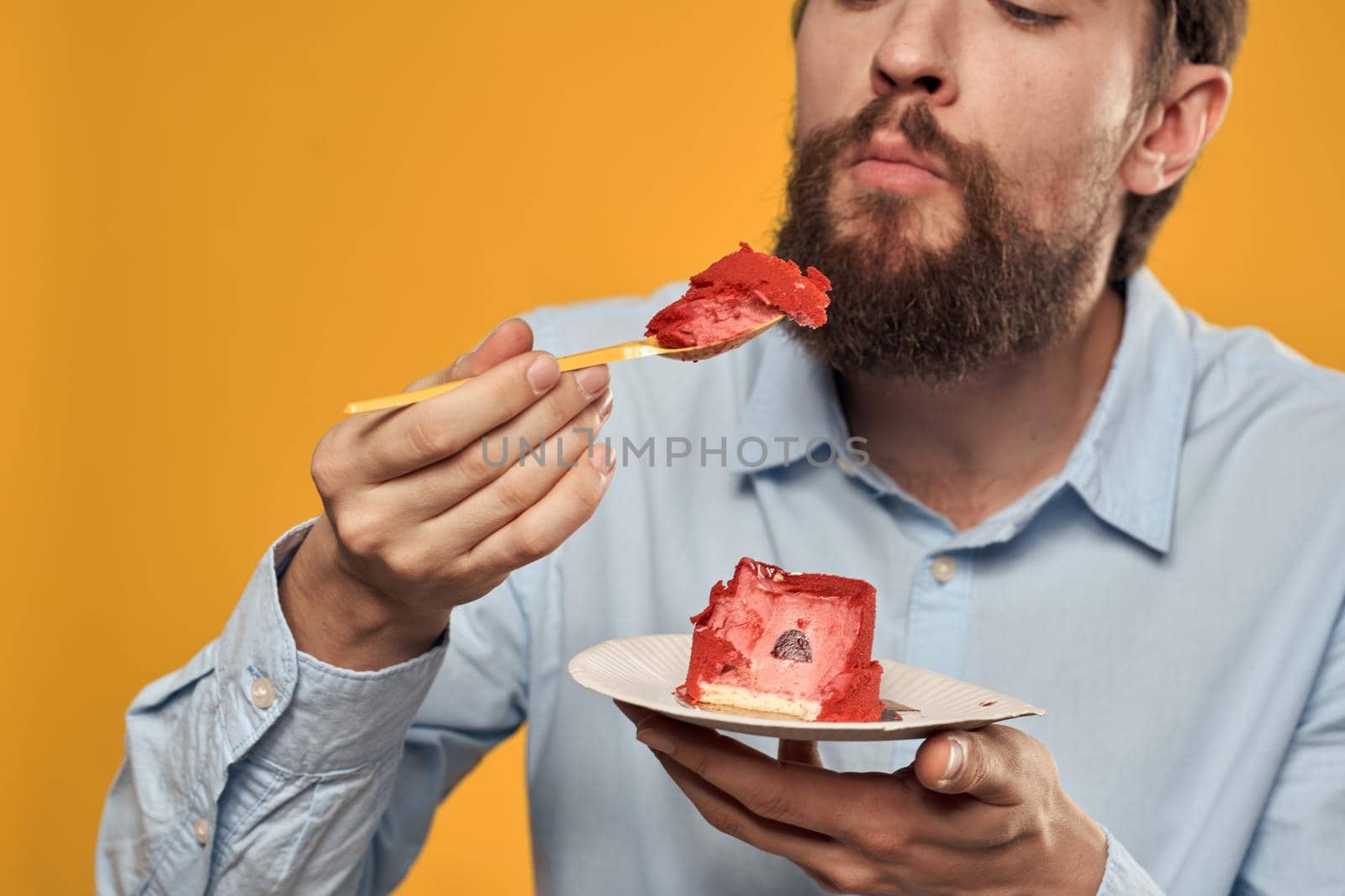 a man with a birthday cake in his hands and in a cap on a yellow background on his birthday. High quality photo